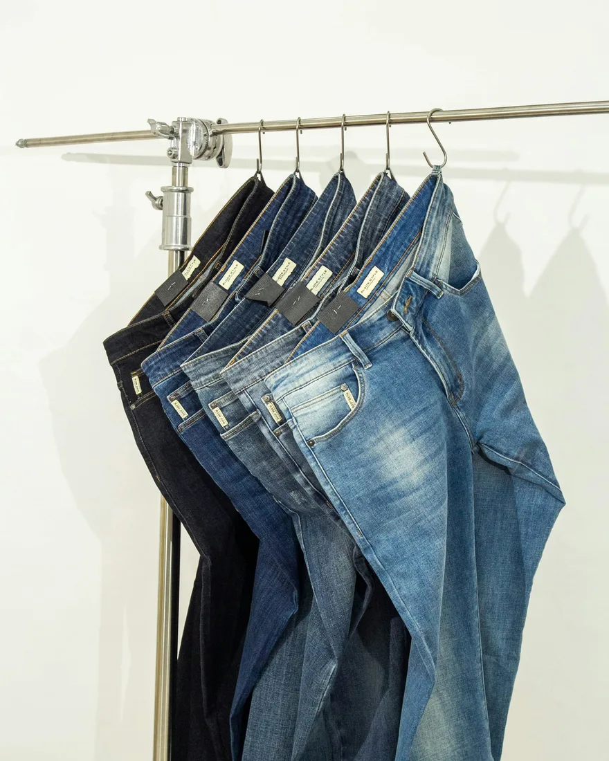 Plusieurs jeans bleus suspendus sur un portant clair